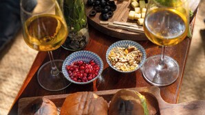 Una mesa de madera con diversos alimentos y copas de vino.