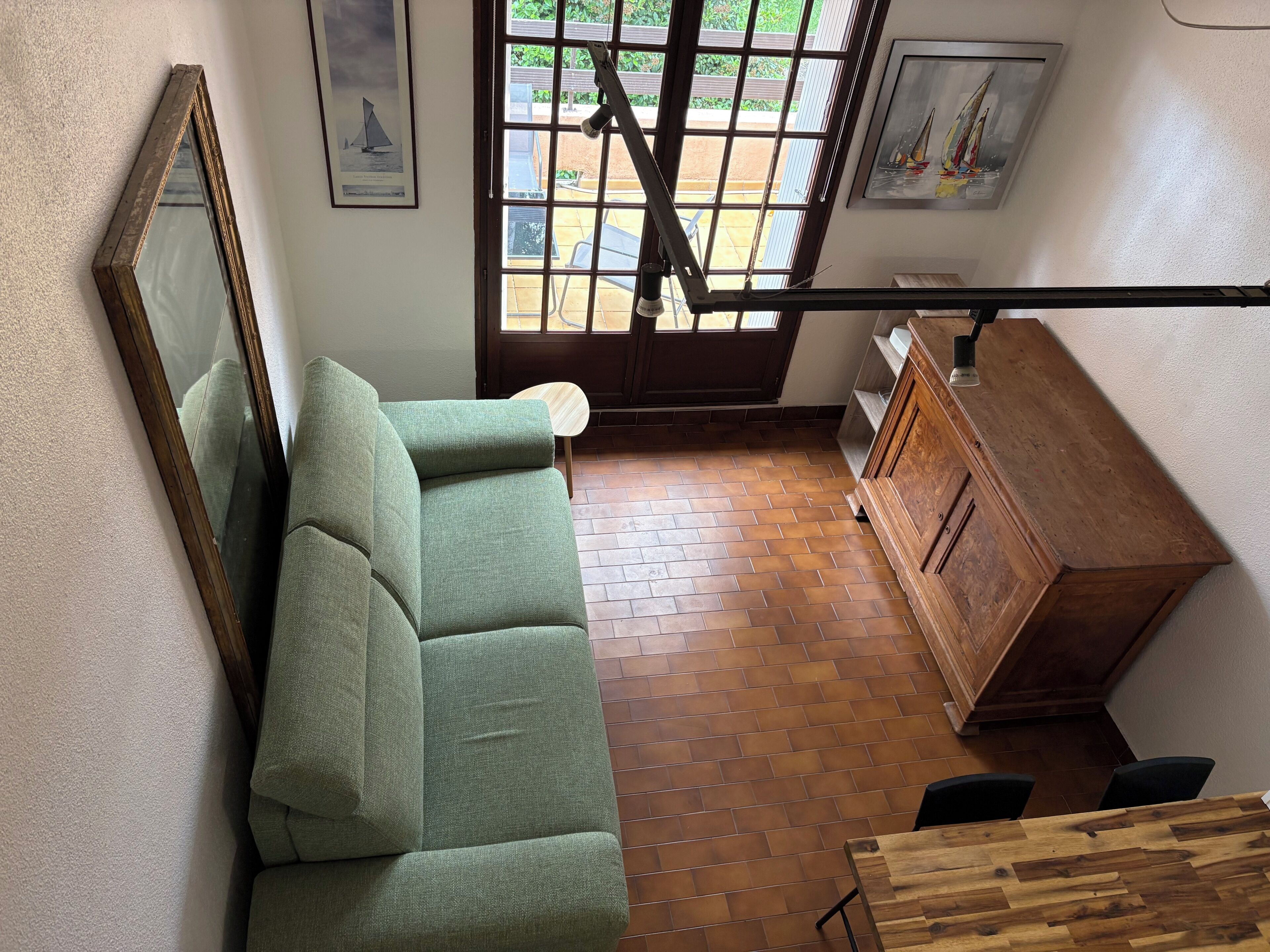Ein Zimmer mit einem grünen Sofa, einem Holzschrank und einem Fenster mit Blick ins Freie.