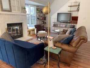 Ein Wohnzimmer mit Kamin, einer Ledersofa, einem blauen Sessel und einem Fernseher.