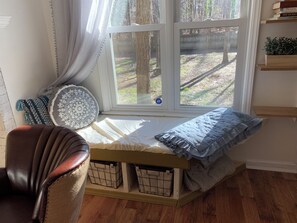 Ein gemütliches Zimmer mit Fensterbank, Stuhl und Bücherregal.