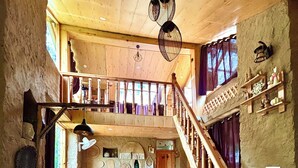A wooden interior with a staircase, a bed, and a dining area. - Cozy, Aesthetic Nature Retreat: Feel Your Soul in the Village Soil (Soil)