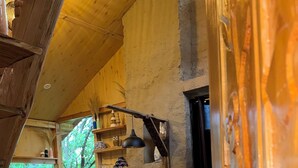 A cozy cabin interior with a wooden dining area, a kitchen with a stone backsplash, and a large window overlooking greenery. - Cozy, Aesthetic Nature Retreat: Feel Your Soul in the Village Soil (Soil)