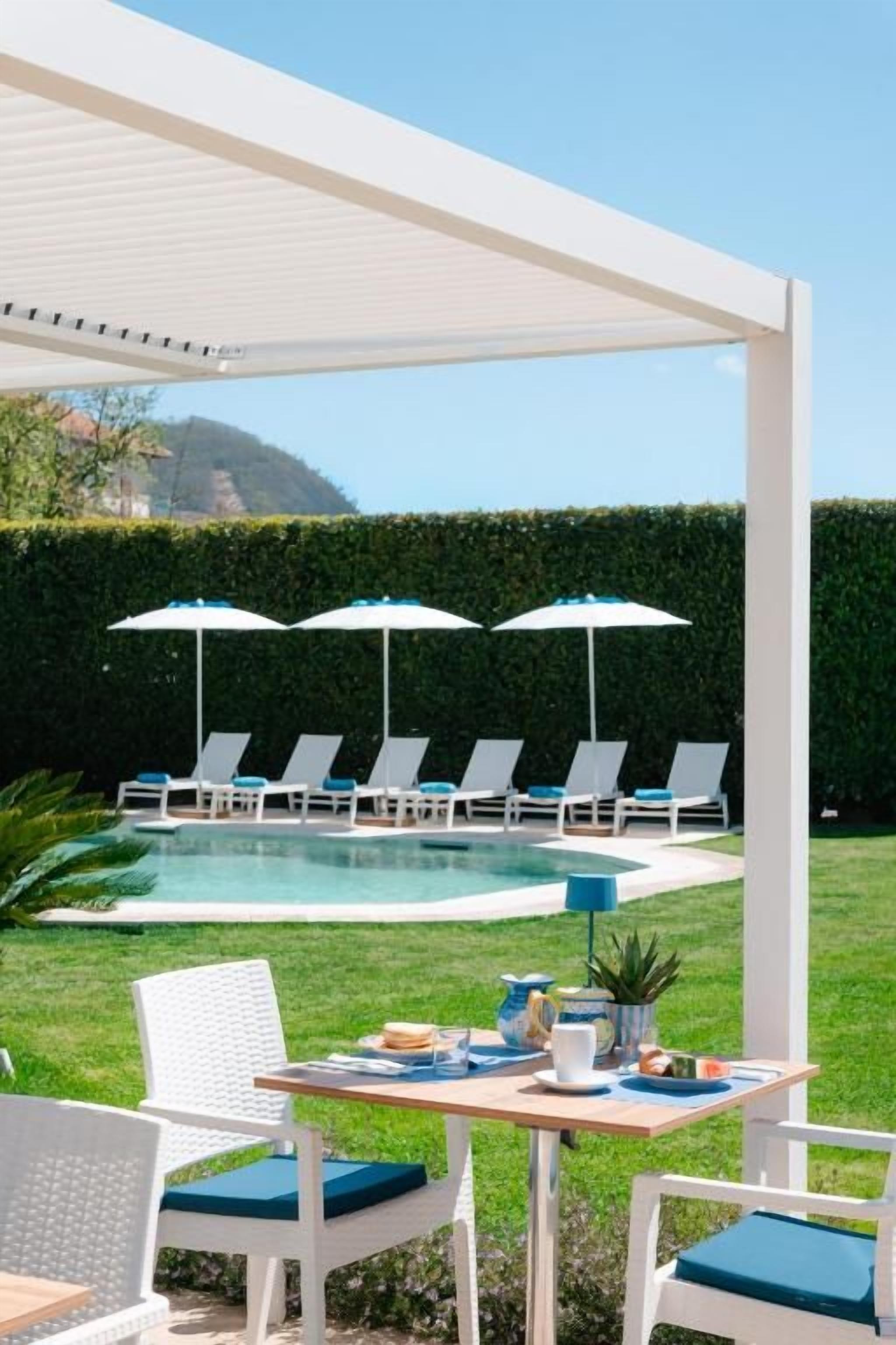 Ein Poolbereich mit Liegestühlen, Sonnenschirmen und einem Tisch, der für das Essen gedeckt ist.