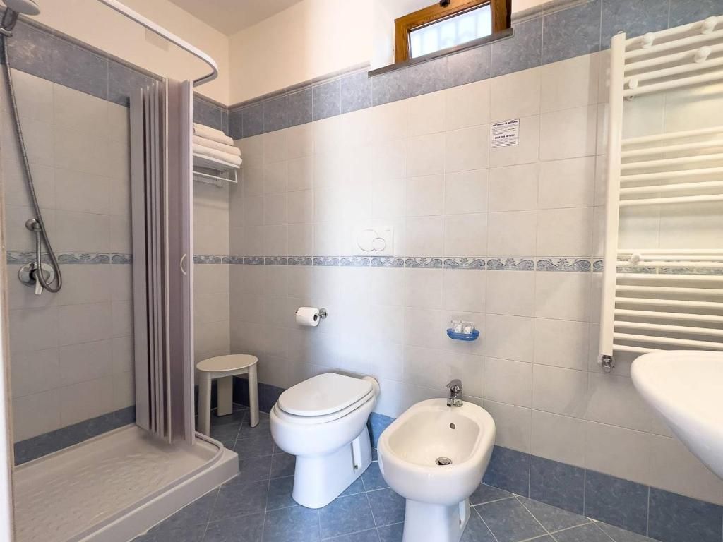 Un baño con ducha, inodoro, bidé y un perchero para toallas.