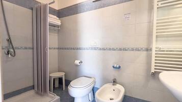 Un baño con ducha, inodoro, bidé y un perchero para toallas.