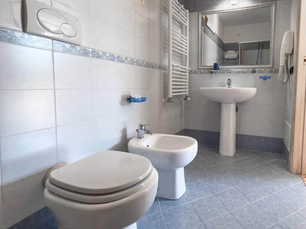 Un baño con inodoro, bidé, lavabo y un perchero para toallas.