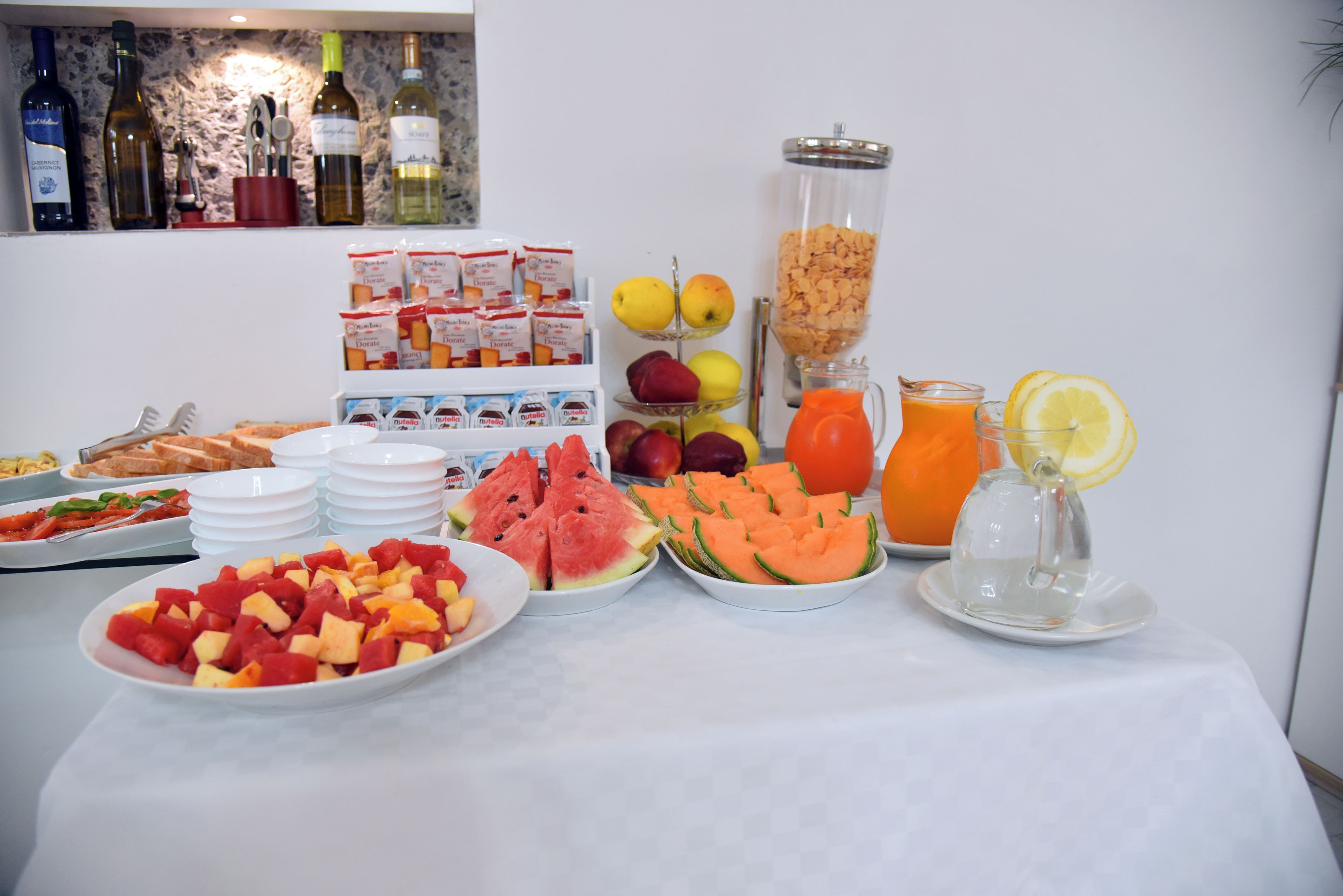 Een ontbijtbuffet met diverse soorten fruit, granen en drankjes.
