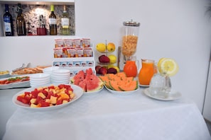 Un bufé de desayuno con diversas frutas, cereales y bebidas.