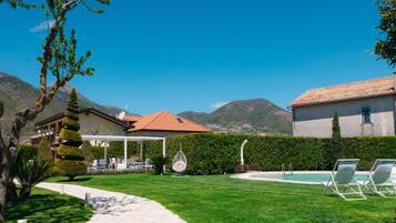 Un espacio exterior bien cuidado con piscina, sillas de descanso y vistas despejadas de las montañas circundantes.