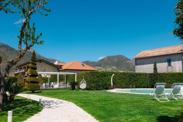 Un espacio exterior bien cuidado con piscina, sillas de descanso y vistas despejadas de las montañas circundantes.