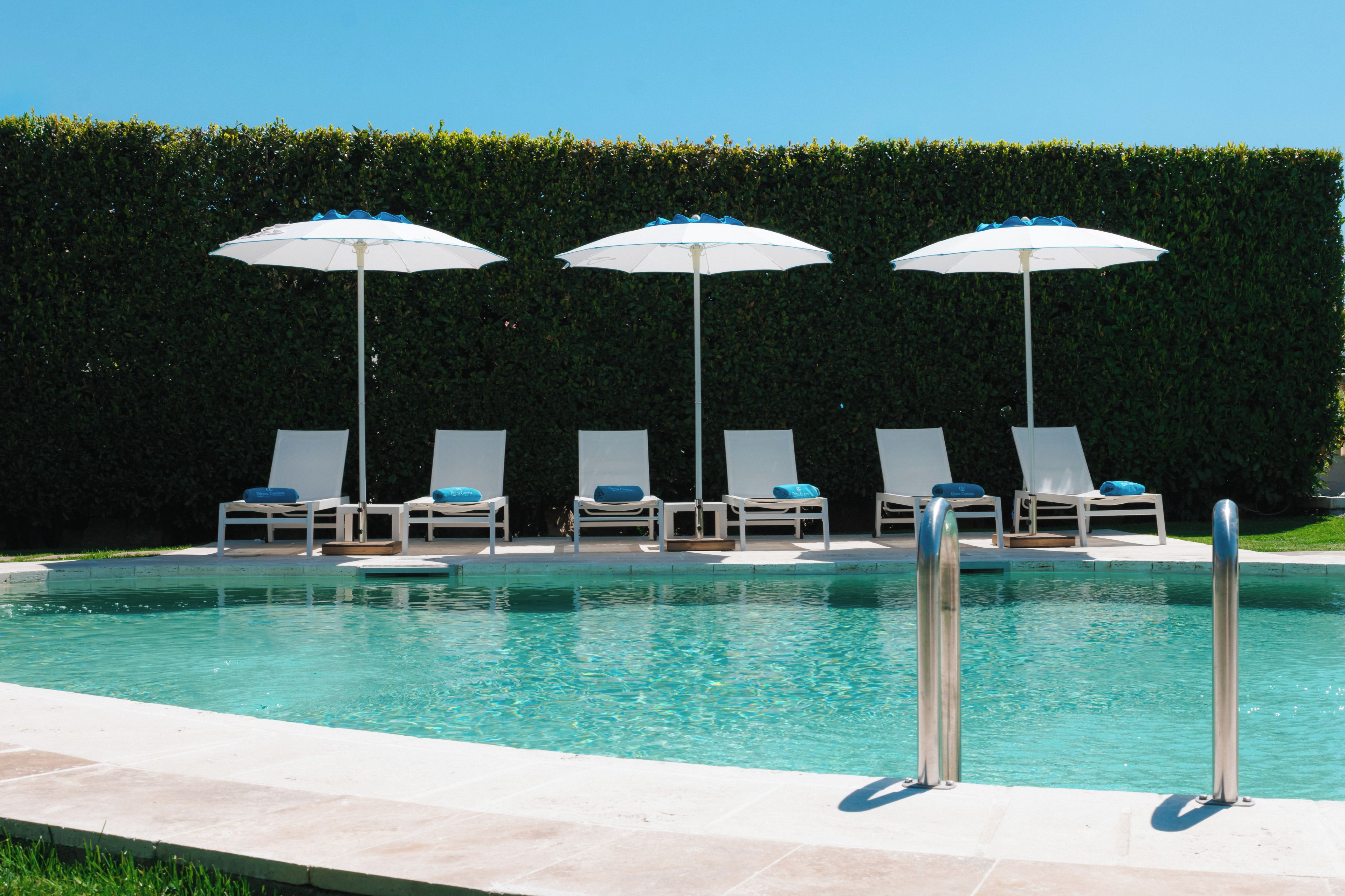 A swimming pool with lounge chairs and umbrellas.