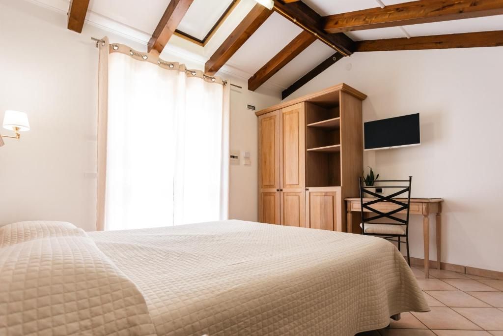 A bedroom with a bed, a desk, a chair, a wardrobe, and a television on the wall.