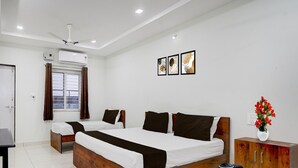 A hotel room with two beds, a wooden headboard, a coffee table with mugs, a cabinet, and a window with curtains. - Deluxe Mini Bypass Nellore Road (Nellore)