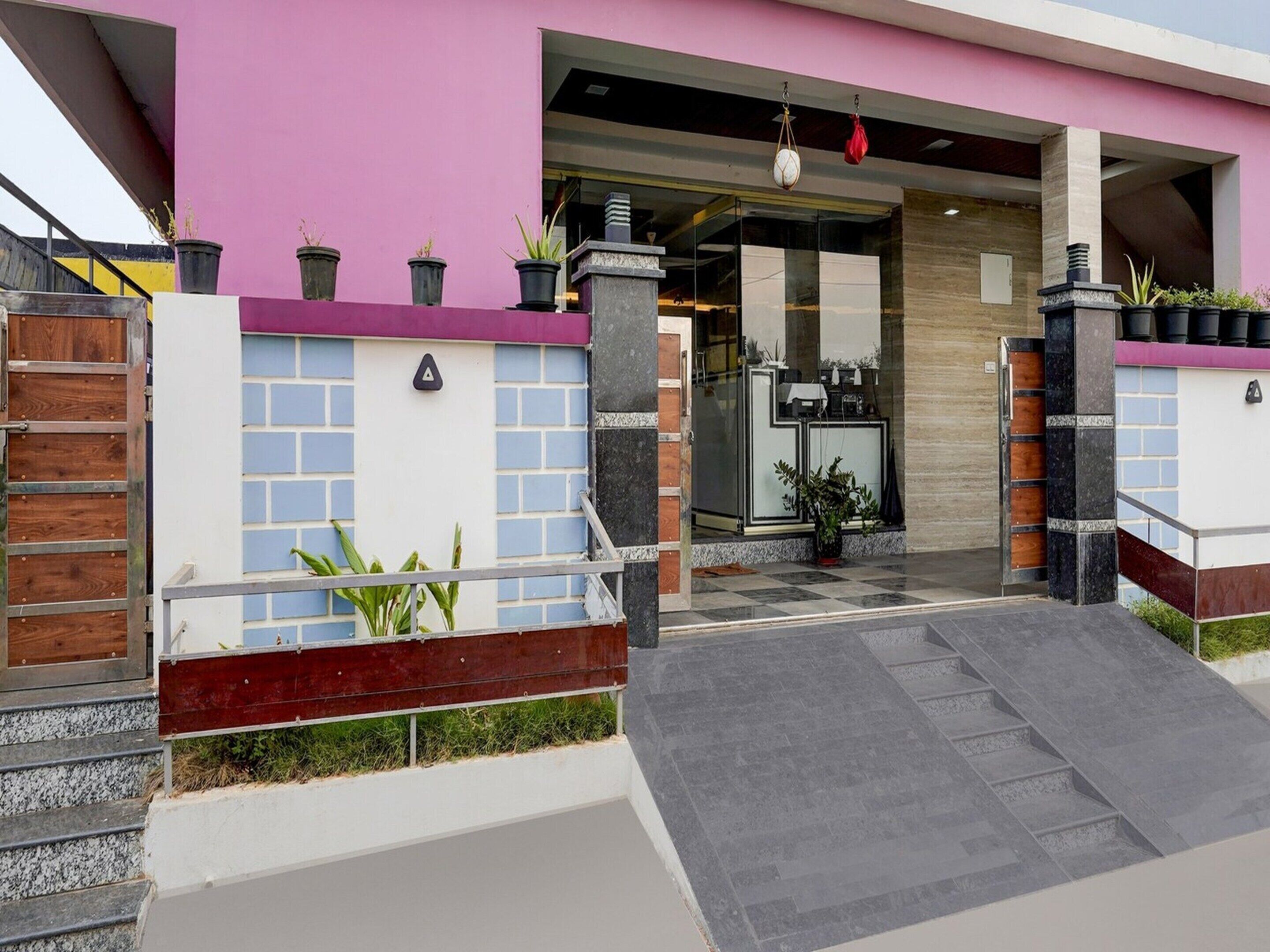 Una entrada moderna de edificio con puerta de vidrio, mostrador de recepción y plantas en macetas.
