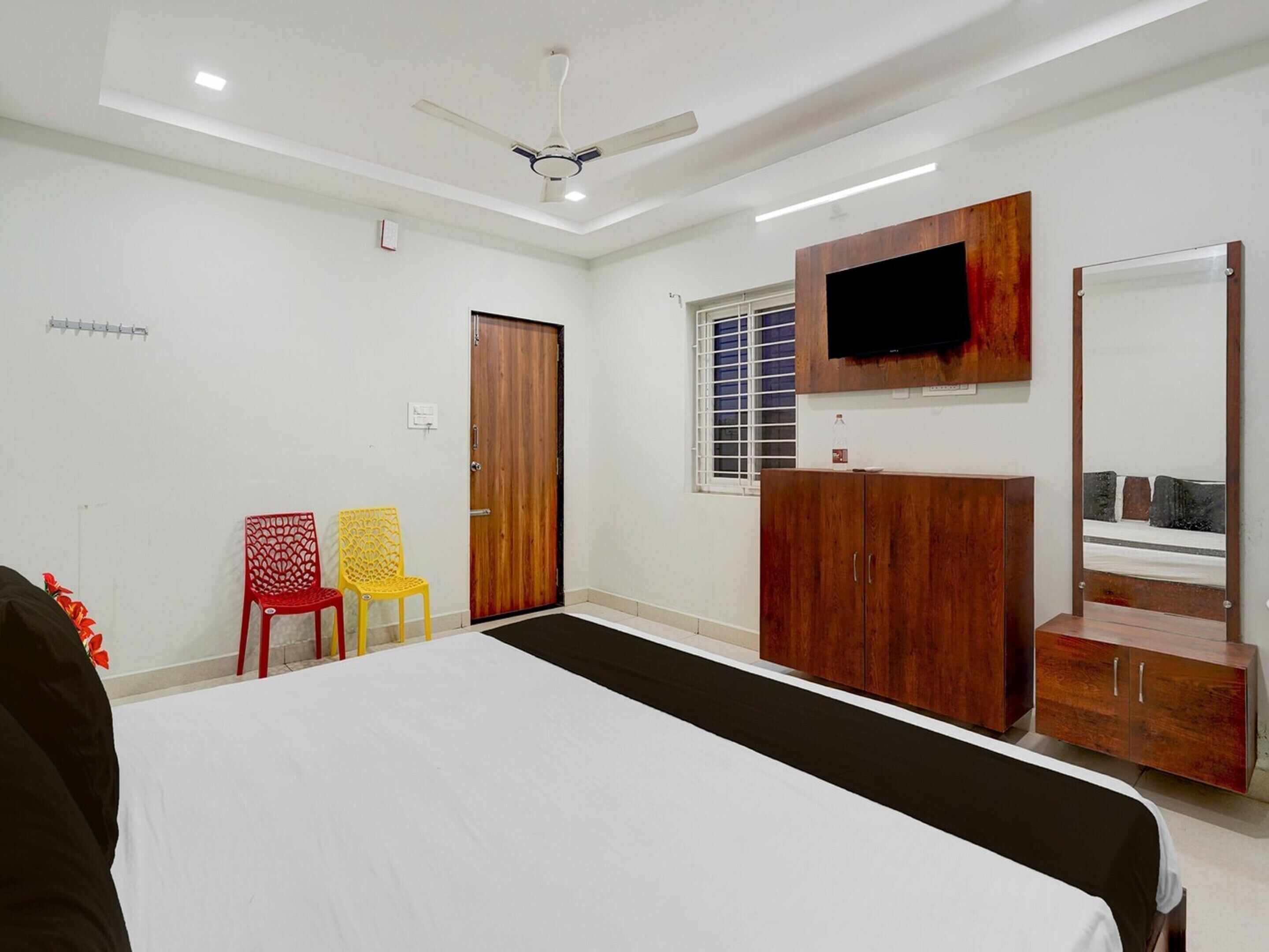 A bedroom with a bed, a wardrobe, a TV, and a ceiling fan.