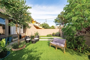 Ein gepflegter Garten mit Rasen, Gartenmöbeln und verschiedenen Pflanzen.