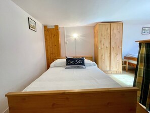 A bedroom with a wooden bed, a wardrobe, and a small desk. - Quiet apartment near beach - 4 guests (Bretignolles-sur-Mer)