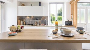 Una cocina moderna con una isla central, armarios blancos y vistas al exterior.