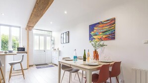 Un comedor con techo de madera, una mesa dispuesta para cuatro personas y un cuadro colorido en la pared.