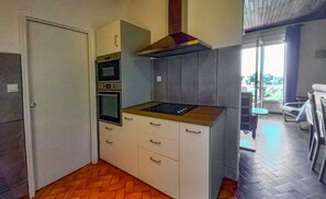 Eine kleine Küche mit einbauendem Backofen, Mikrowelle und Kochfeld.
