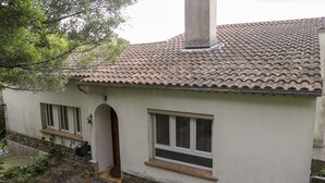Edifici de planta baixa amb teulada de rajola, una xemeneu, un petit porxo amb escales i una finestra amb persianes.