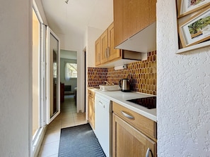 Una cocina estrecha con armarios de madera, un salpicadero de azulejos y una ventana.