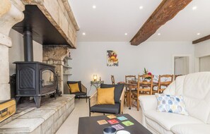 Un salon chaleureux avec une cheminée, un coin repas et un canapé.