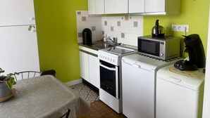 A compact kitchen with white cabinets, a microwave, a coffee maker, and a toaster. - Chic city center studio, parking - 2 guests (Sablé-sur-Sarthe)