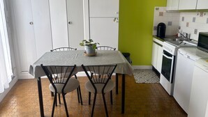 A kitchen with a dining table, chairs, a potted plant, a sink, a stove, and a refrigerator. - Chic city center studio, parking - 2 guests (Sablé-sur-Sarthe)