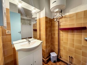 Ein Badezimmer mit Waschbecken, Spiegel, Dusche und gefliesten Wänden.