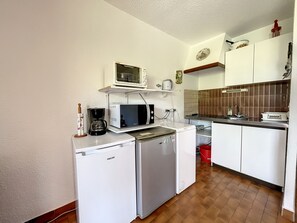 Eine kompakte Küchenzeile mit Mikrowelle, Kaffeemaschine und kleinem Kühlschrank.