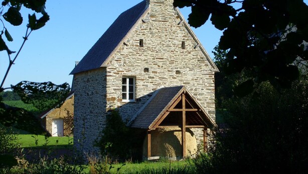 Ein Steinhaus mit einem dreieckigen Dach und einem daran angebauten Holzbau.