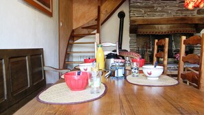 Ein Holztisch mit Untersetzern, einer roten Schüssel, einem Glas und einer gelben Flasche.