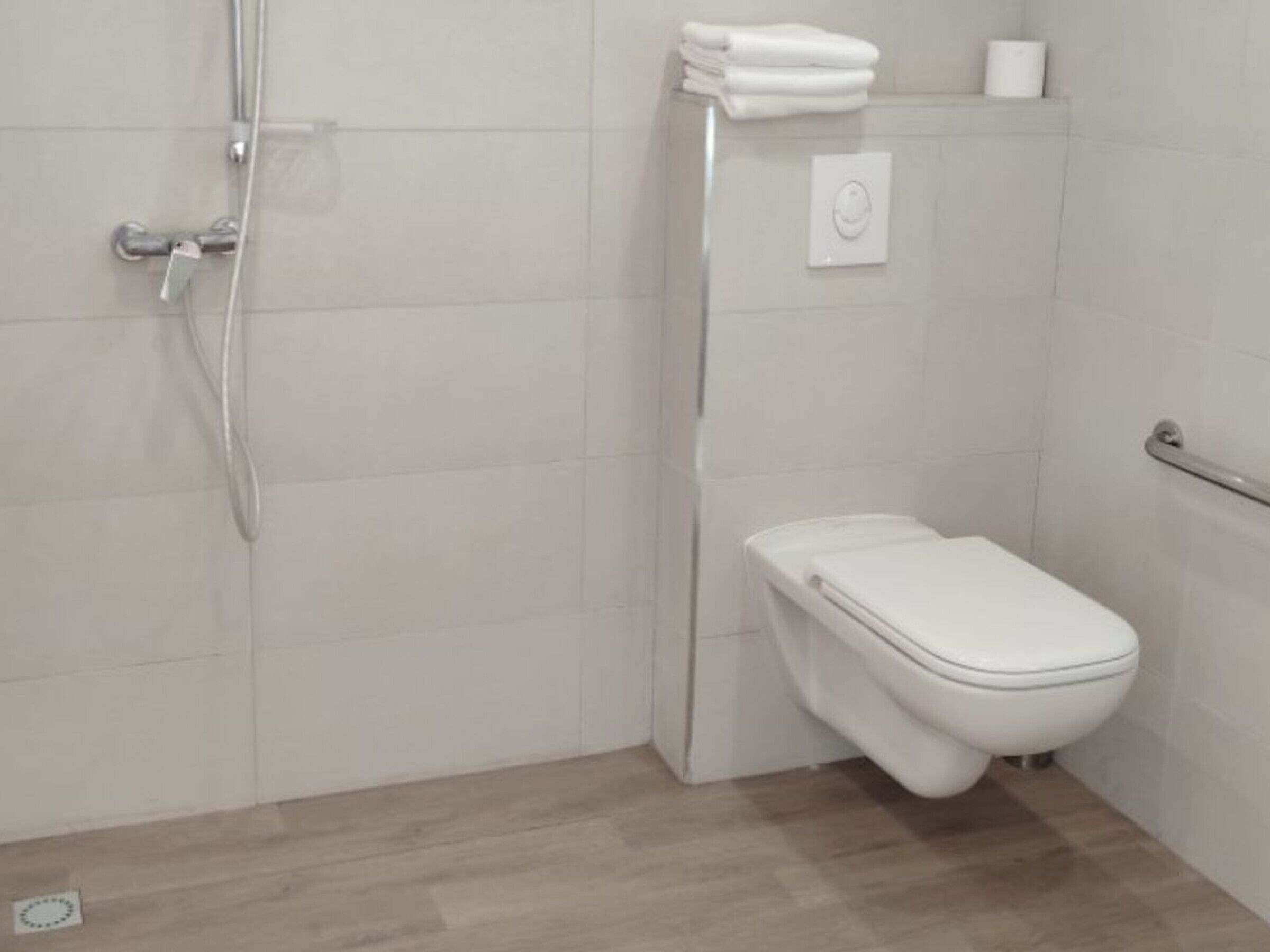 Ein Badezimmer mit Toilette, Dusche und Handtuchhalter.