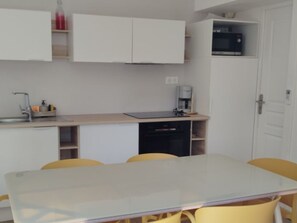 A compact kitchen with a sink, microwave, and coffee maker. There is a dining table with chairs. - Mobile home with AC - 4 guests (Sainte-Marie)
