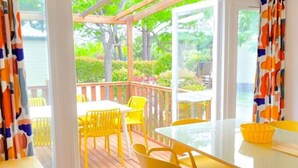 A covered outdoor area with a table and chairs, a view of greenery, and a wooden deck. - Mobile Home with Terrace and AC - 6 guests (Sainte-Marie)