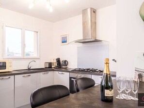 Eine moderne Küche mit Gasherd, Mikrowelle, Kaffeemaschine und einer Champagnerflasche.