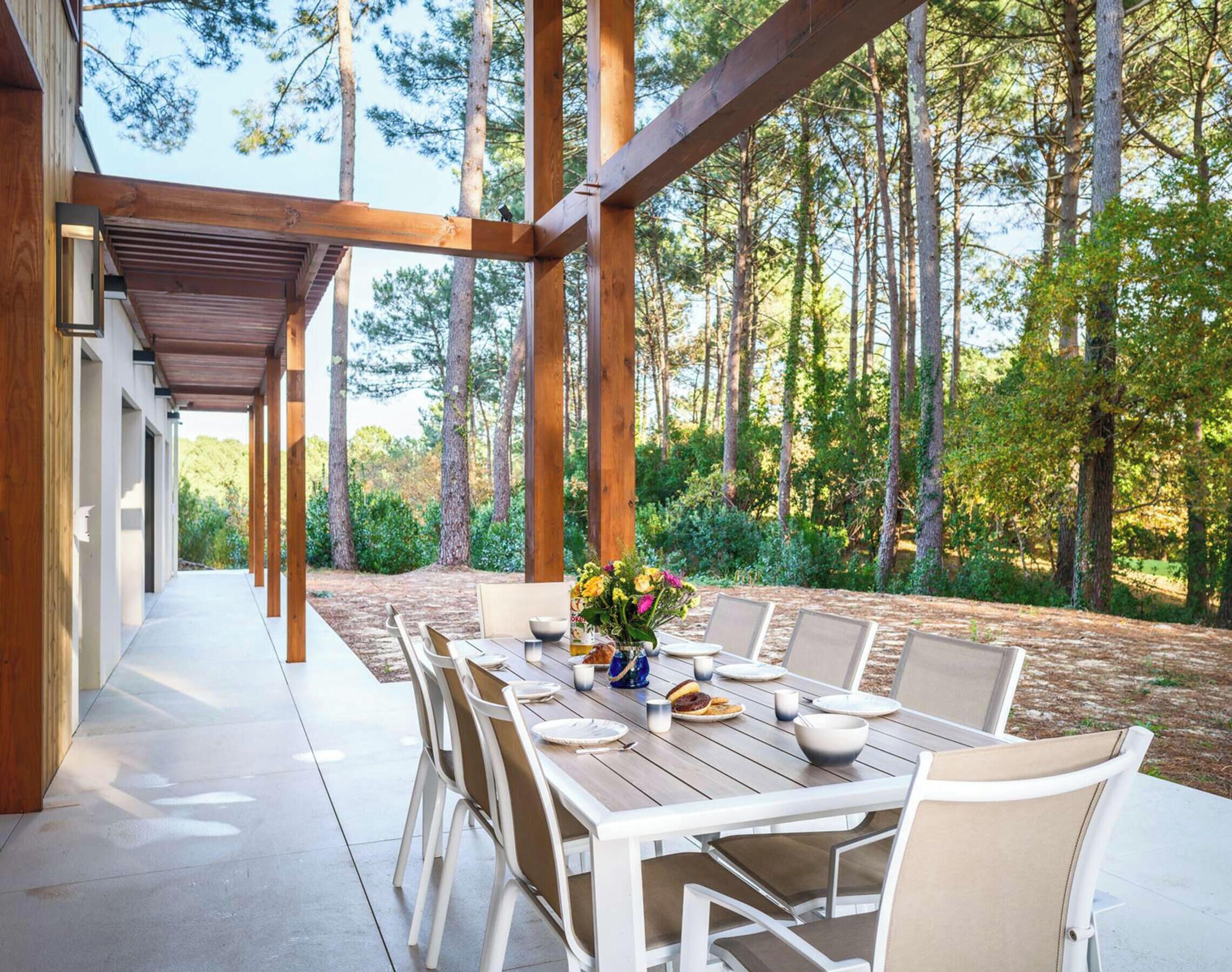 An outdoor dining area with a wooden pergola, a table set for four, and chairs.