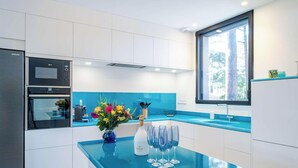 Una cocina moderna con armarios blancos, encimera azul, horno empotrado y un amplio ventanal.