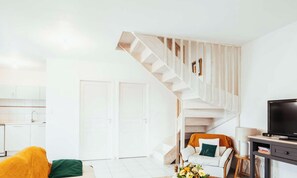 Ein modernes Wohnzimmer mit Treppe, Fernseher und Sofa.