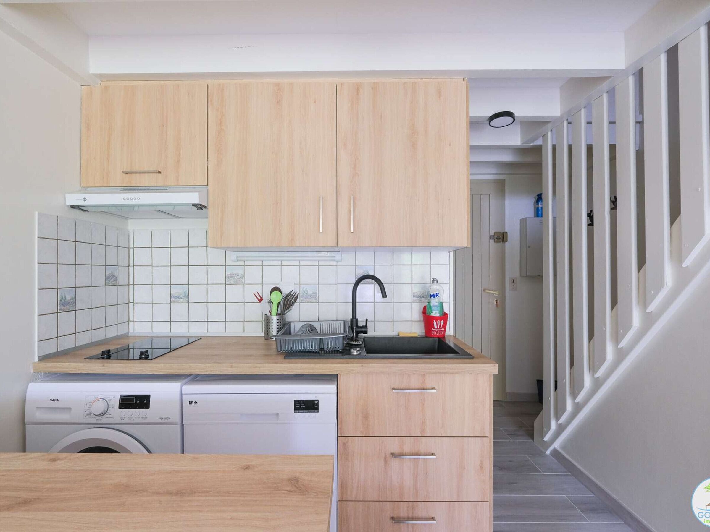A compact kitchen with wooden cabinets, a built-in dishwasher, and a sink.