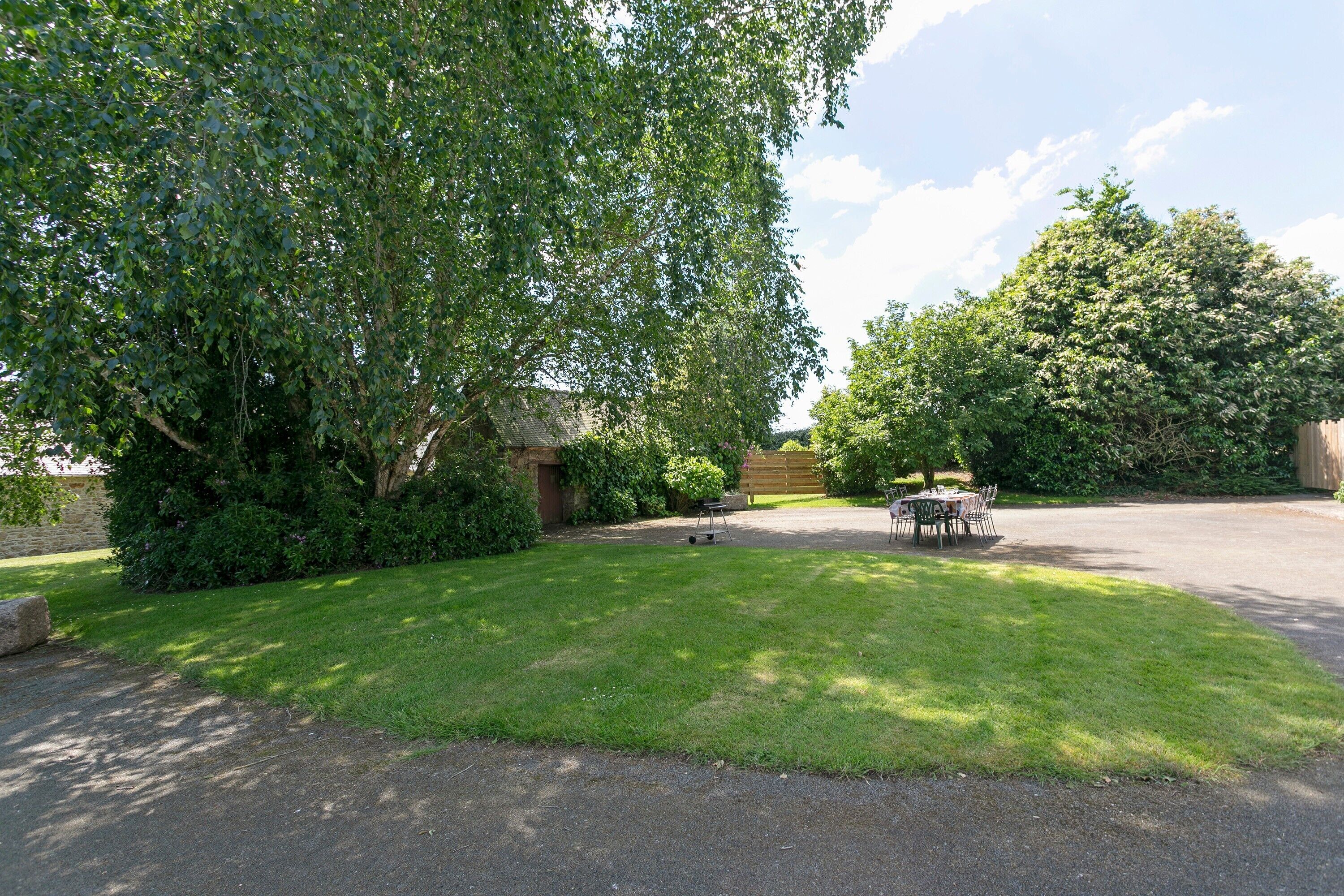 A well-maintained lawn with a barbecue area and a paved driveway.