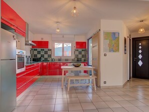 Eine moderne Küche mit roten Schränken, weißen Arbeitsplatten und einem Essbereich mit Tisch und Bank.