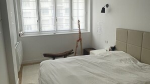 A bedroom with a large bed, a window with blinds, a standing lamp, and a radiator. - Apartment PARIS 1 MINUTE WALKING TO TOUR EIFFEL (Paris)