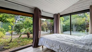 A bedroom with a large window, wooden flooring, and a bed. - Charming wooden house near lake - 9 guests (Biscarrosse)