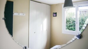 A room with a large mirror, a wardrobe, a window with a view of greenery, and a hanging lamp. - Charming wooden house near lake - 9 guests (Biscarrosse)