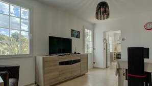 Een moderne keuken met een televisie, eethoek en een klok aan de muur.
