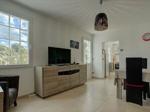 Eine moderne Küche mit Fernseher, Essbereich und einer Uhr an der Wand.