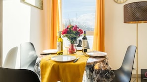 A dining table with yellow tablecloth, wine bottles, glasses, and a vase of flowers. - Cozy apartment in the heart of Biscarrosse - 4 guests (Biscarrosse)