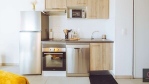 A modern kitchen with stainless steel appliances, wooden cabinets, and a black countertop. - Cozy apartment in the heart of Biscarrosse - 4 guests (Biscarrosse)